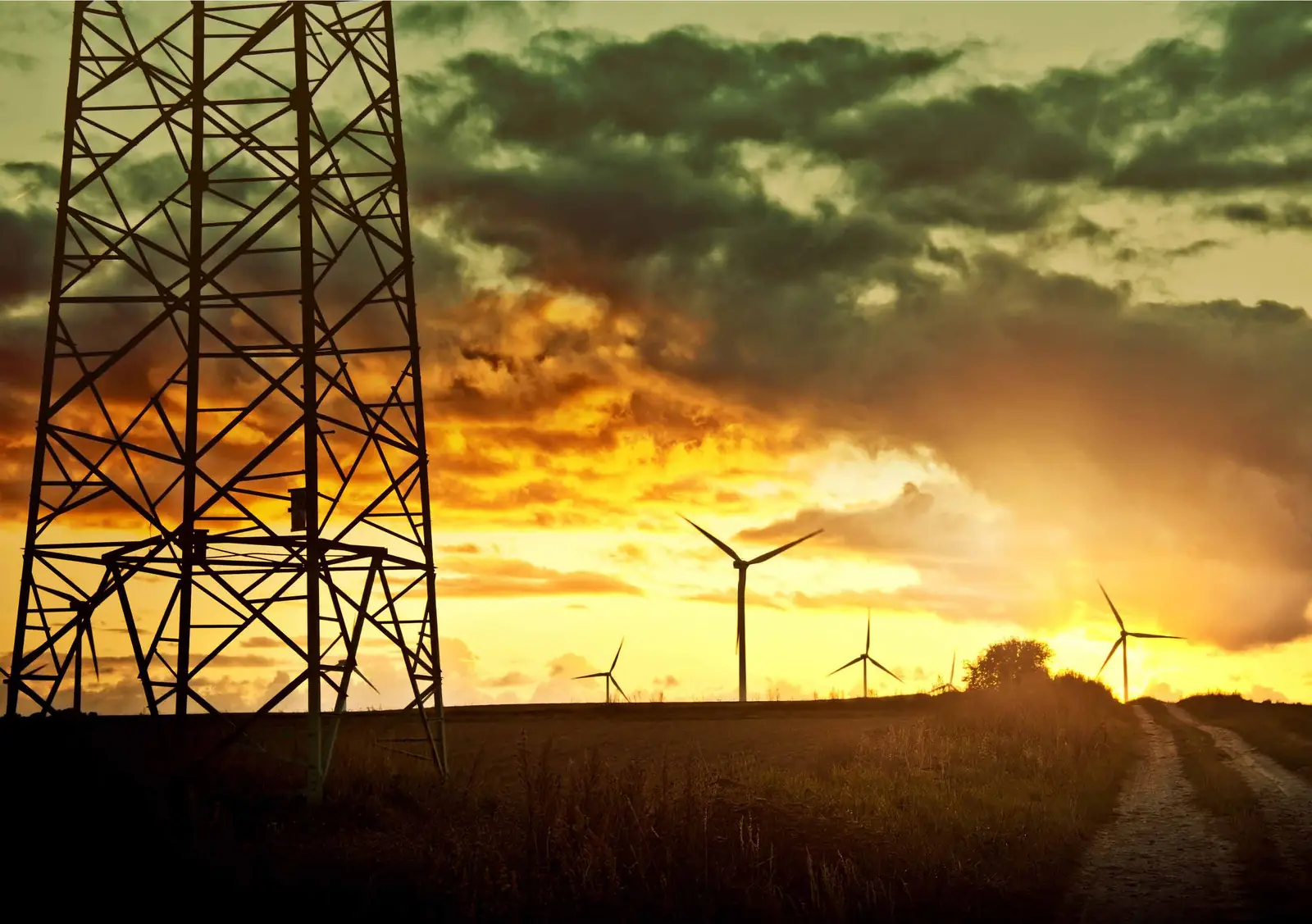 Pylône électrique au coucher du soleil, éoliennes en arrière-plan
